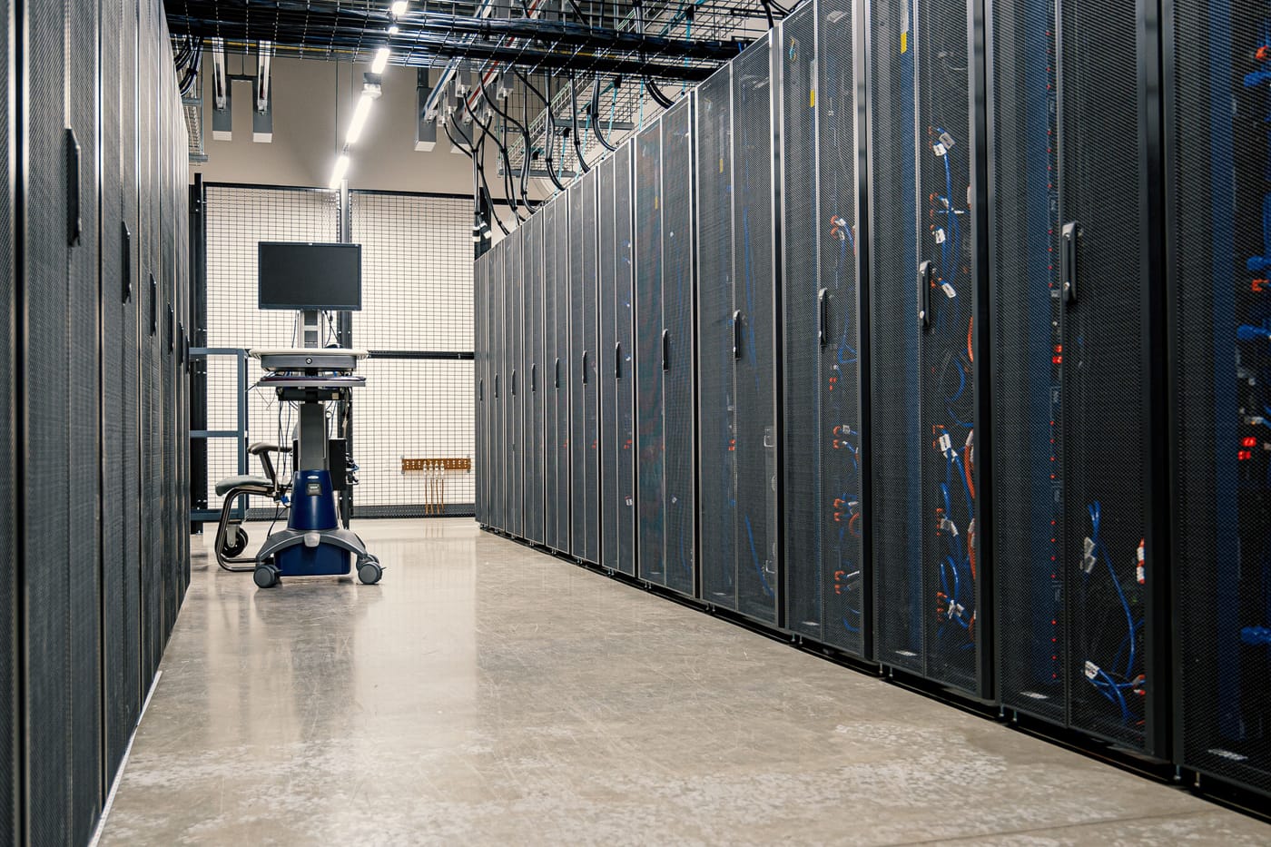 Commercial equipment room with enclosed network racks and overhead cable tray pathways